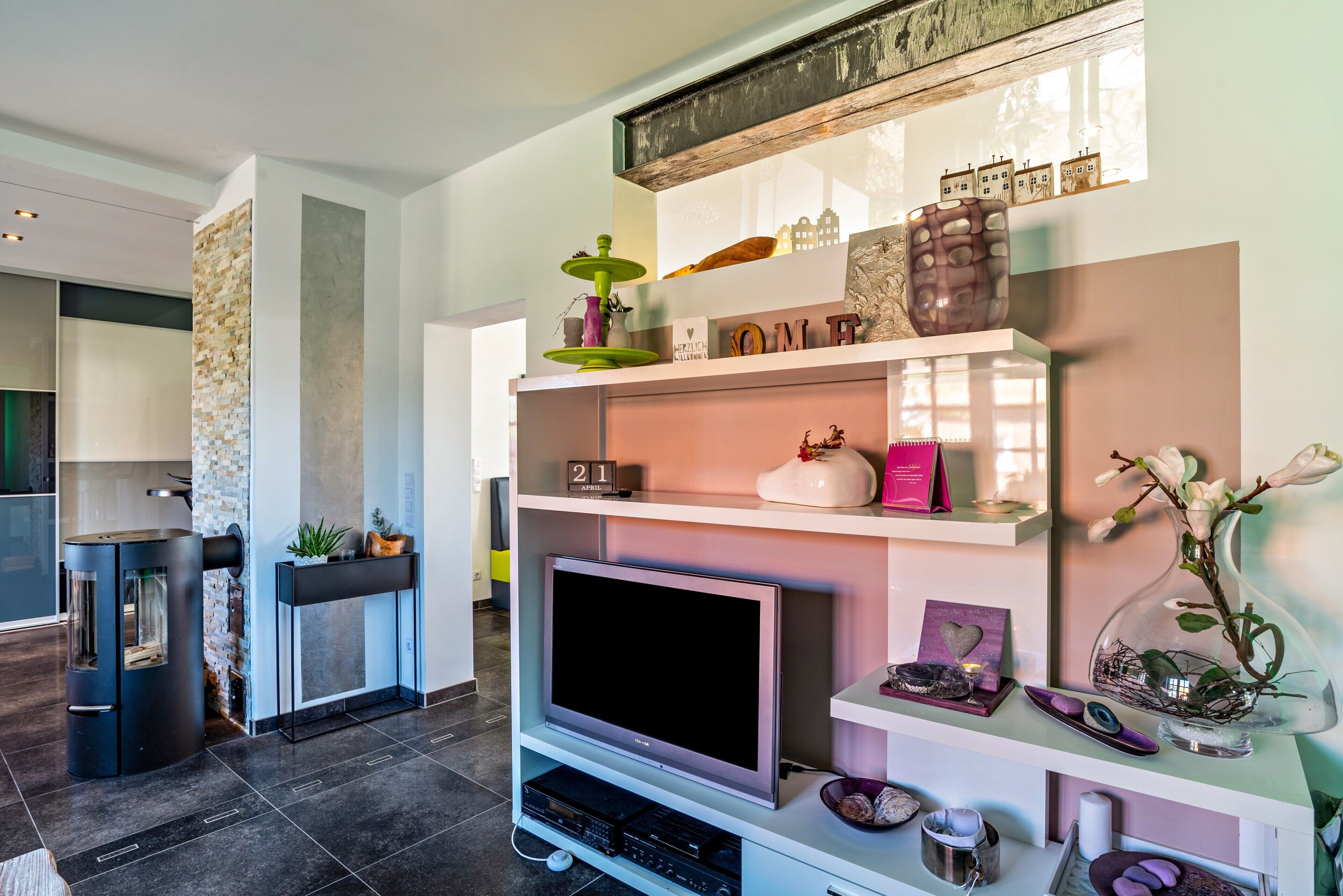 Ein modernes Wohnzimmer mit Kamin, Fernseher und dekorativen Regalen.
