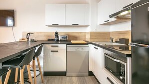 A modern kitchen with white cabinets, a black countertop, a dishwasher, a microwave, and a refrigerator.