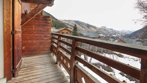 A wooden balcony with a view of a valley and mountains.