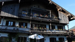 A traditional wooden chalet with multiple balconies, each adorned with potted plants. - Ferienwohnung bis 4 Personen (Kiefersfelden)