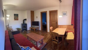 A cozy living room with a sofa, a coffee table, a TV, and a fireplace. - Ferienwohnung bis 4 Personen (Kiefersfelden)