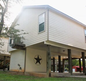 A two-story building with a balcony on the first floor, a star symbol on the exterior wall, and a garage in the background.