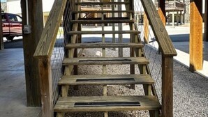 Una escalera de madera con barandilla metálica que lleva a la entrada de un edificio.