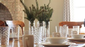 A dining table set with white dishes, glasses, and a decorative plant in a glass vase.