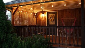 A wooden building with a covered porch, a lattice fence, and a hanging swing.