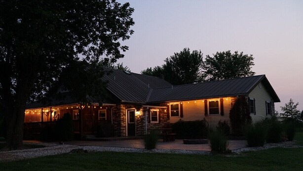 A two-story building with a covered patio area, a stone facade, and a metal roof.