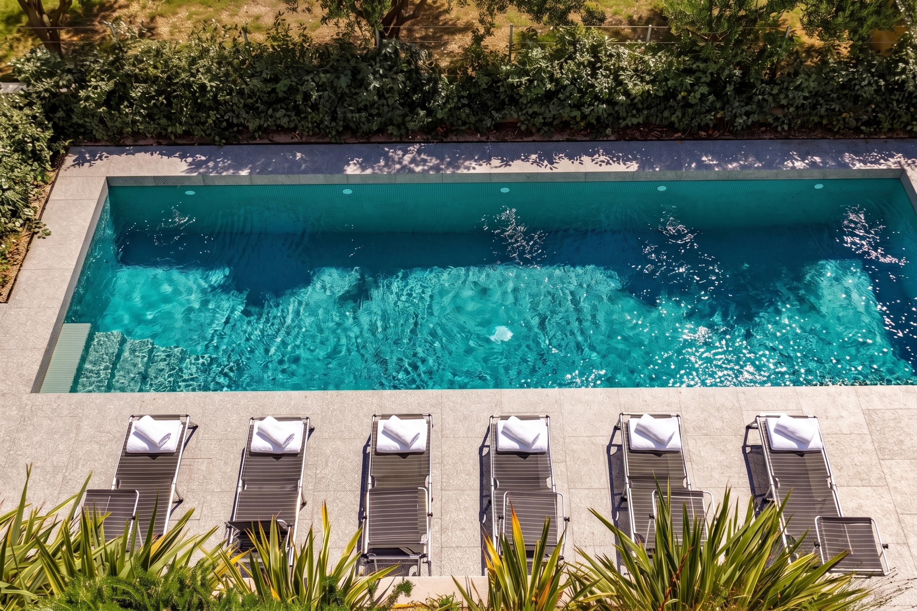 Une piscine rectangulaire à l’eau d’un bleu limpide, entourée d’une terrasse carrelée.