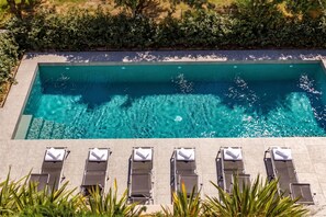 Ein rechteckiger Swimmingpool mit klarem, blauem Wasser, umgeben von einer gefliesten Liegefläche.