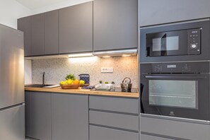 A modern kitchen with grey cabinetry, a built-in oven, and a microwave. - Pool Apartment Sapore Di Mare 4, Baška, Croatia (Baška)