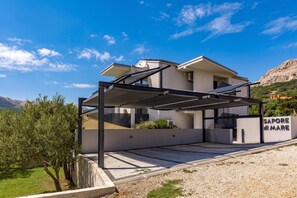 Een modern huis met twee verdiepingen, een overdekt terras, zonnepanelen en een bord waarop staat 'Sapore del Mare'.