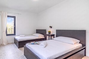 Une chambre moderne avec deux lits, une petite table de chevet avec une lampe et une fenêtre avec des rideaux.