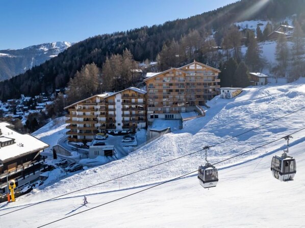 A ski resort with a multi-story building, ski lifts, and a snowy mountain backdrop.