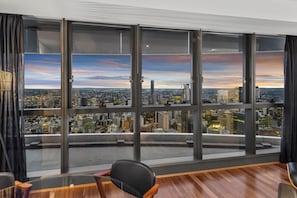 Enjoy a panoramic city view from the expansive windows in this stylish room, featuring a sleek leather chair and a small side table.