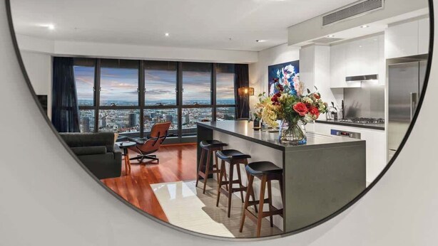 Eine moderne Küche mit Stadtblick, ein Essbereich mit Sofa und Stühlen sowie eine Bar mit Hockern.