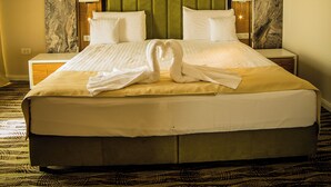 A hotel room with a large bed, two bedside tables, a headboard with a marble-like design, and a green upholstered headboard panel. - President Spa Baile Felix (Sânmartin)