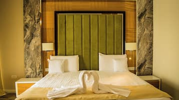 A hotel room with a large bed, two bedside tables, a headboard with a marble-like design, and a green upholstered headboard panel.