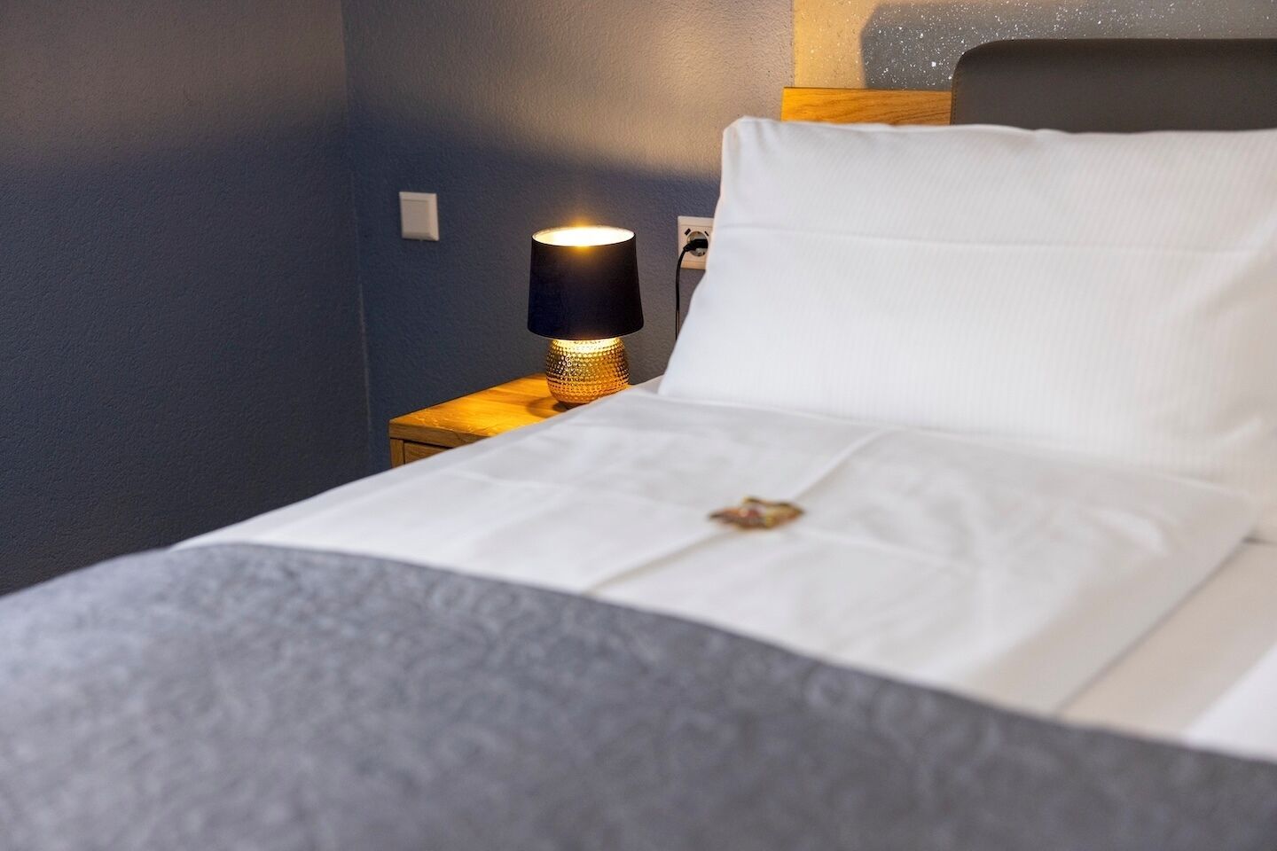 Una cama bien hecha con un almohadón blanco y un adorno decorativo sobre la colcha.