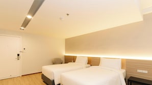 A hotel room with two beds, a desk, a chair, a door, and a ceiling light. - Le Srivaree Suvaranabhumi Airport Hotel (Bang Phli)