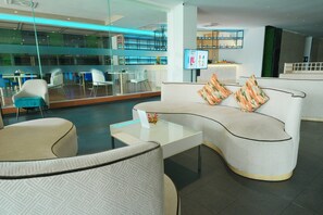 A modern lounge area with a curved sofa, a glass coffee table, and a seating area with chairs. - Le Srivaree Suvaranabhumi Airport Hotel (Bang Phli)