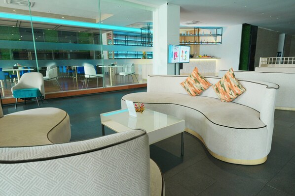 A modern lounge area with a curved sofa, a glass coffee table, and a seating area with chairs.
