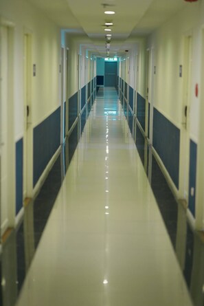 A long, narrow hallway with doors on both sides, leading to an exit at the end. - Le Srivaree Suvaranabhumi Airport Hotel (Bang Phli)