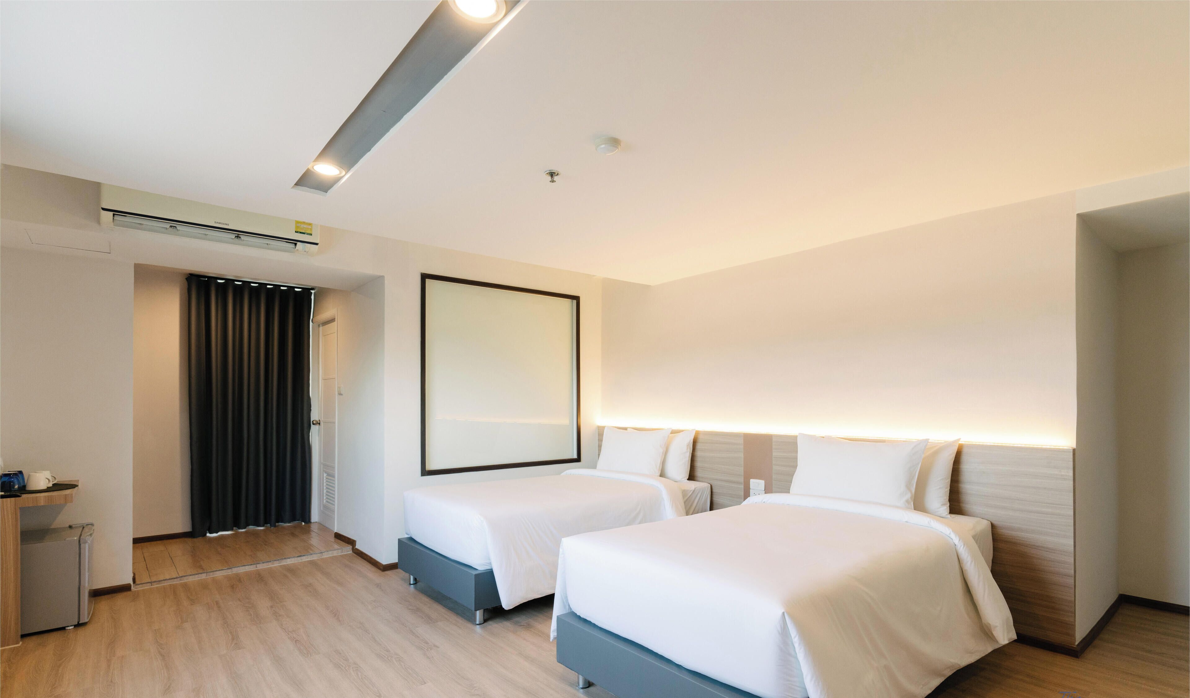 Una habitación de hotel moderna con dos camas, un escritorio pequeño y un espejo.