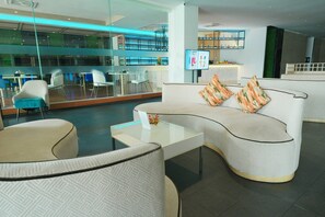 A modern lounge area with a curved sofa, a glass coffee table, and a seating area with chairs. - Le Srivaree Suvaranabhumi Airport Hotel (Bang Phli)