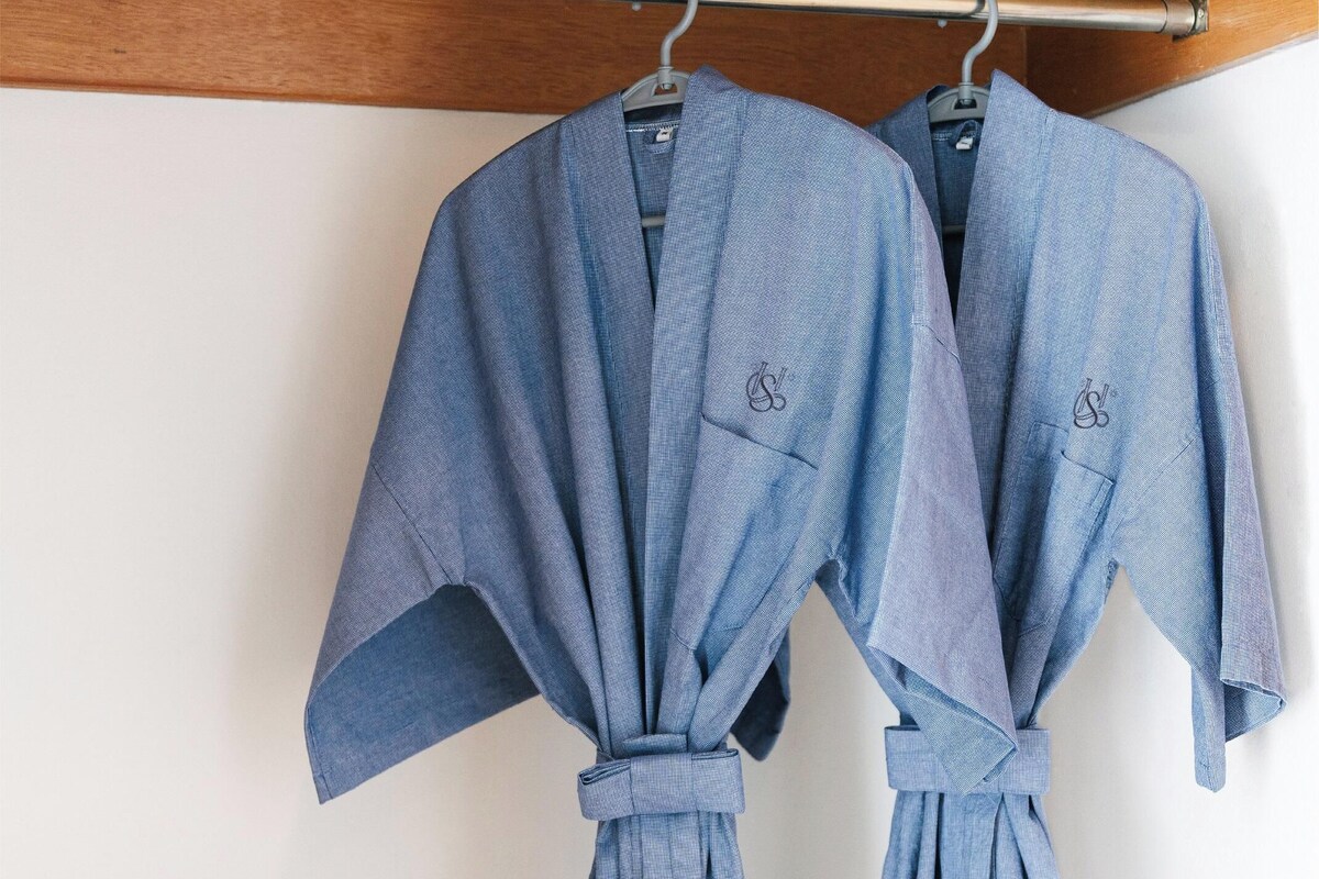 Two blue robes hanging on a metal rod in a room with wooden paneling.