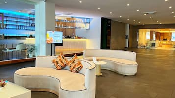A modern lobby with curved seating, a reception desk, and a bar area.