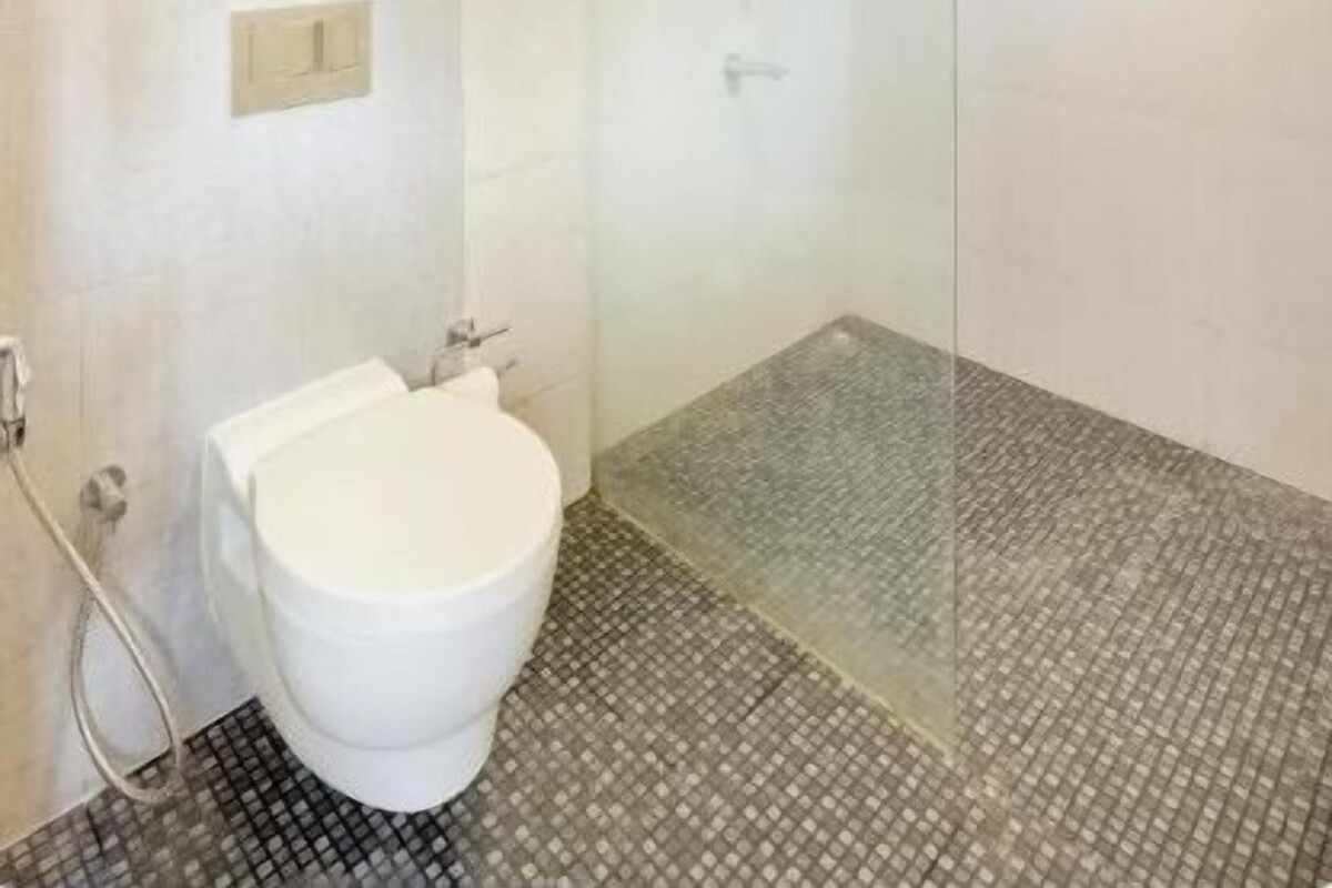 A modern bathroom with a glass-enclosed shower, a toilet, and a towel rack.