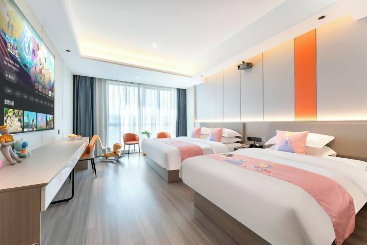 Une chambre d’hôtel moderne équipée de deux lits, d’un bureau et d’un grand écran de télévision.