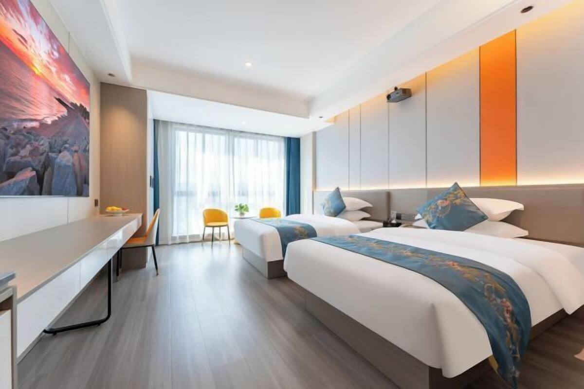 Une chambre d’hôtel moderne avec deux lits, un bureau et un grand tableau au mur.