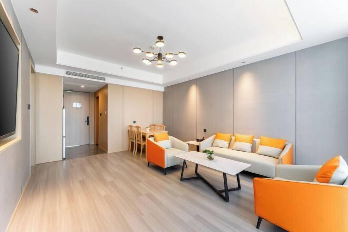 Un salon moderne comprenant un ensemble de canapés, une table basse et un coin repas avec des chaises.