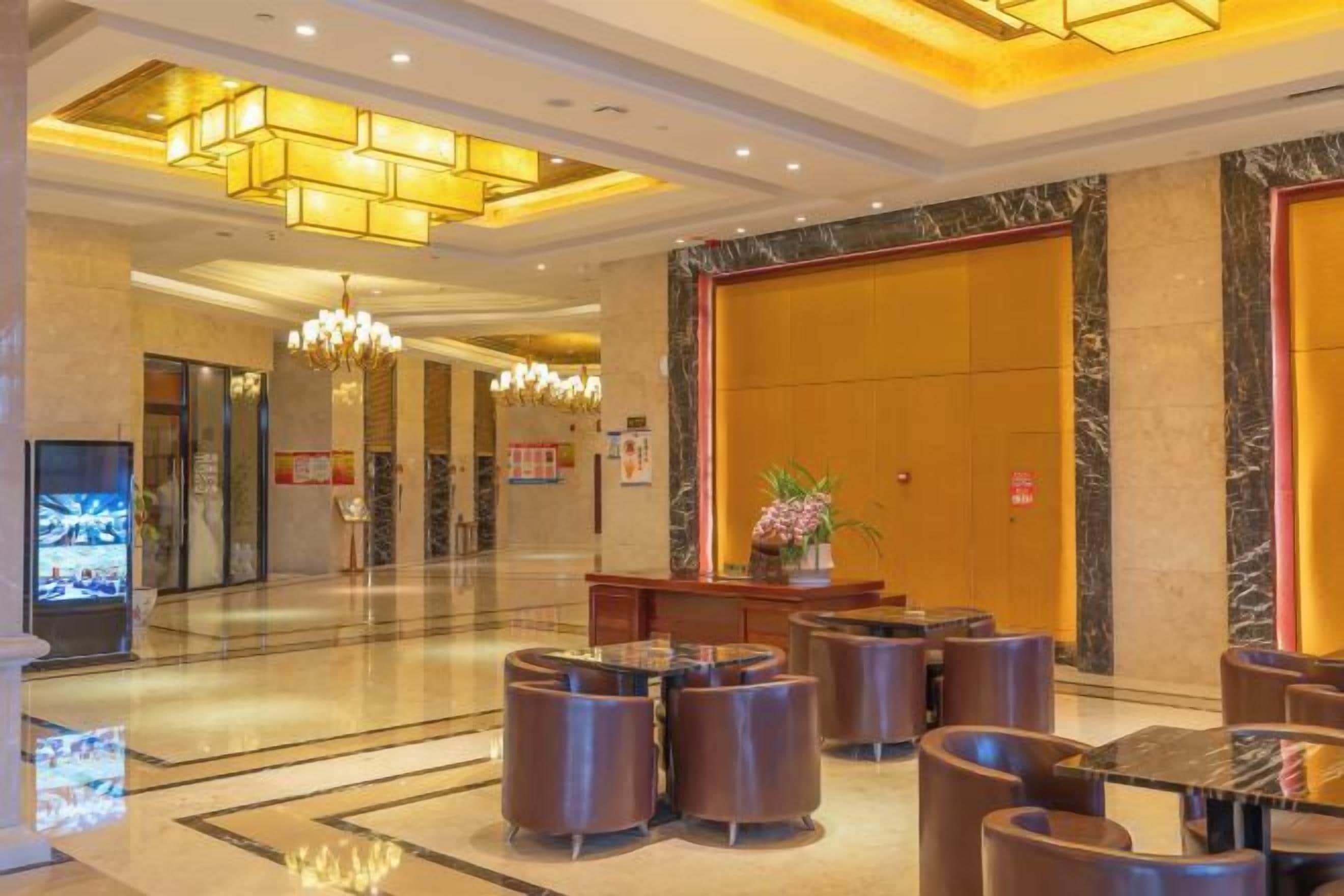 A hotel lobby with a reception desk, seating area, and a large mirror.