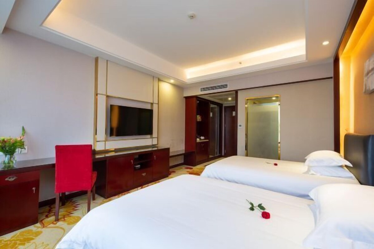 Une chambre d’hôtel avec deux lits, une télévision, un bureau et une chaise rouge.