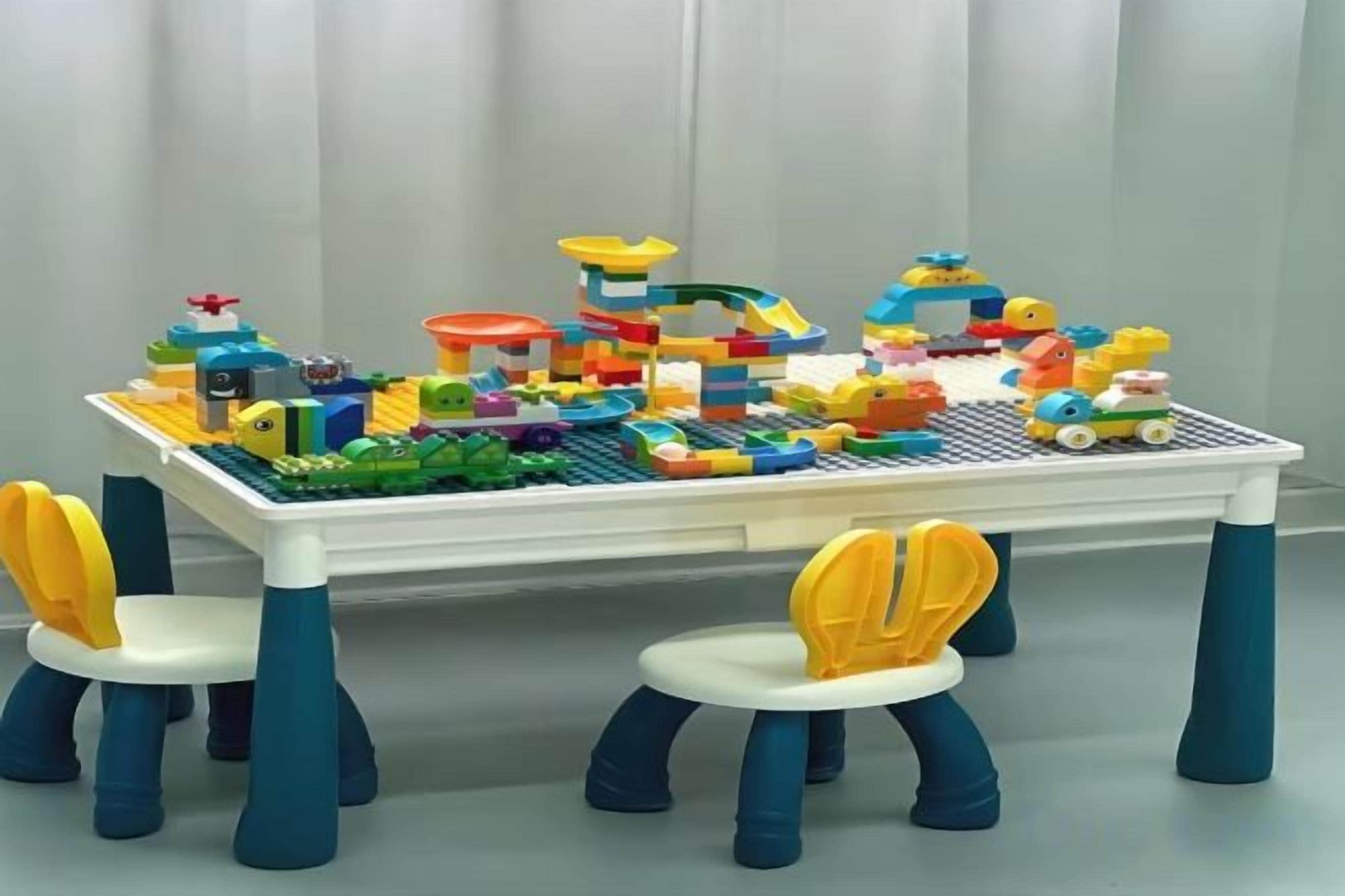 A table with a LEGO cityscape and four chairs with yellow and blue accents.