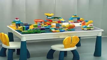 A table with a LEGO cityscape and four chairs with yellow and blue accents.