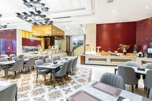Ein modernes Restaurant mit mehreren Tischen, Stühlen, einer Küche und einem Empfangsbereich.