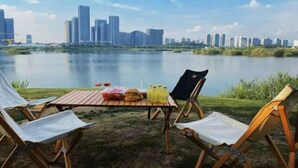 Zona de comedor junto al lago con una mesa para dos, con vistas a un horizonte urbano.