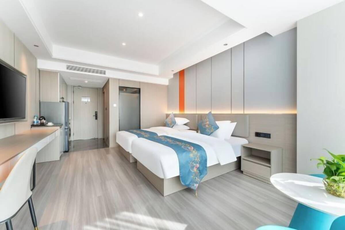 Une chambre d’hôtel moderne dotée d’un grand lit, d’un bureau, d’une télévision à écran plat et d’une salle de bain avec un lavabo et un miroir.