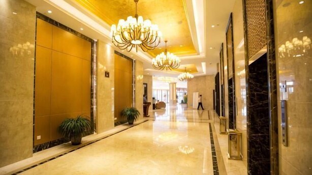 Un pasillo de hotel con candelabros, suelos de mármol y un vestíbulo pulido.