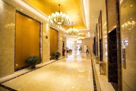 A hotel corridor with chandeliers, marble floors, and a polished lobby.. Hengsheng International Hotel