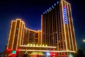 A multi-story hotel with illuminated vertical lines and signage. - Hengsheng International Hotel (Yiwu)