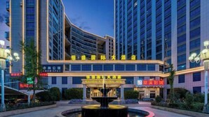 Un hotel moderno con una entrada destacada, una fuente central e iluminación atractiva.
