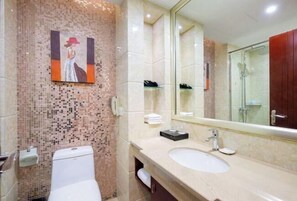 Een badkamer met een wand van mozaïektegels, een toilet, een wastafel, een spiegel en een douche.