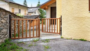 A stone wall, a wooden gate, and a building with a yellow exterior.