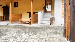 A building with a wooden porch, a bench, a staircase, and a door with a heart-shaped decoration.