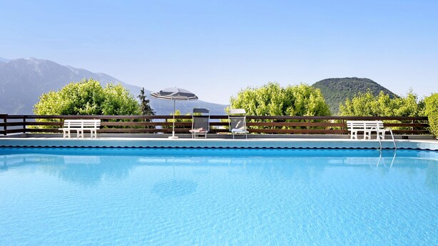 A swimming pool with lounge chairs and an umbrella, surrounded by trees and mountains. - Apartment "Casa Lucy" with Lake View, Shared Pool & Wi-Fi (Tremosine sul Garda)