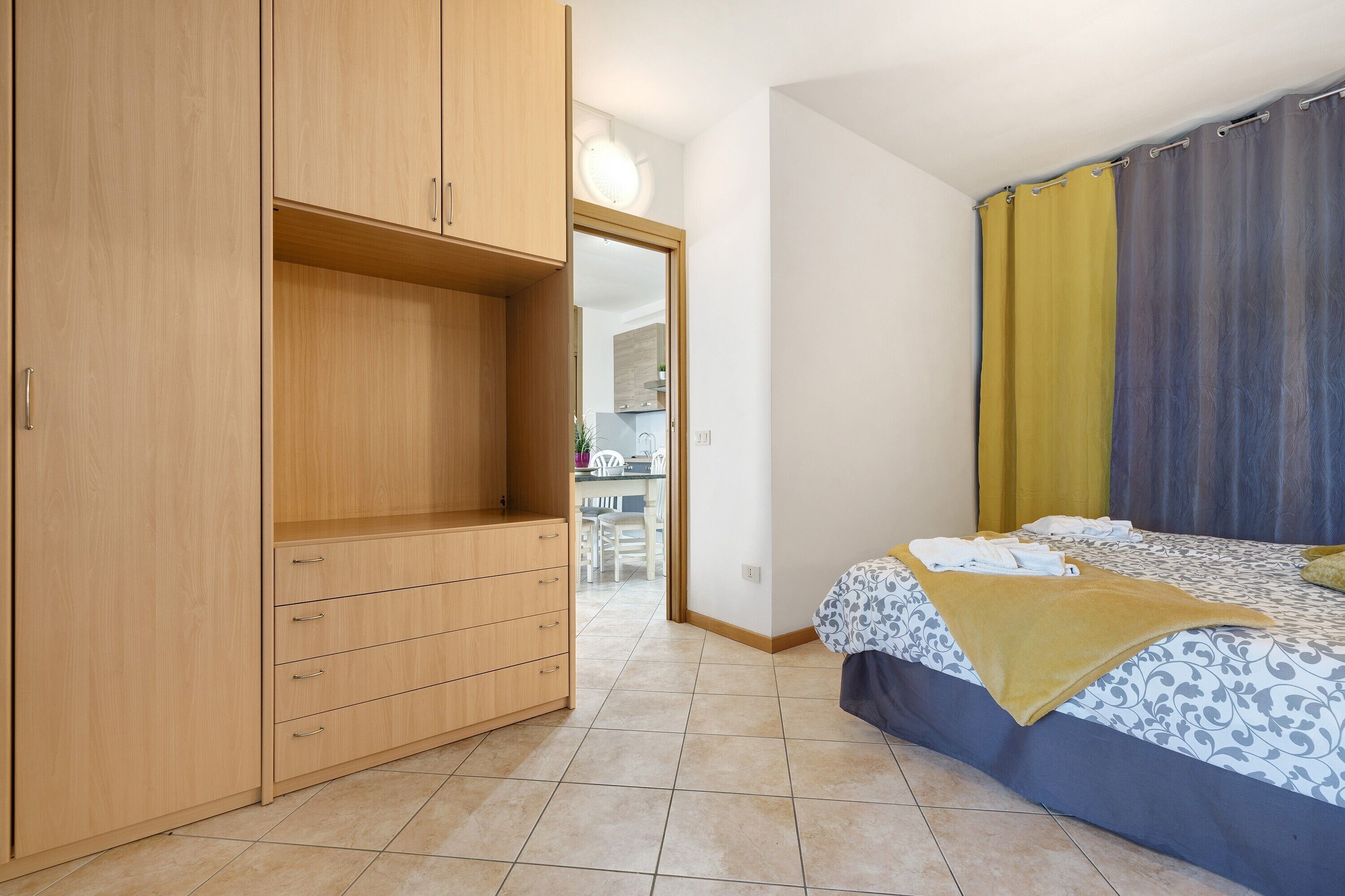 A bedroom with a bed, a wardrobe, and a bathroom visible through an open door.