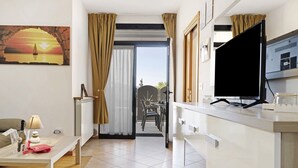 A modern hotel room with a dining area, a TV, and a view through a window. - Apartment "Casa Lucy" with Lake View, Shared Pool & Wi-Fi (Tremosine sul Garda)